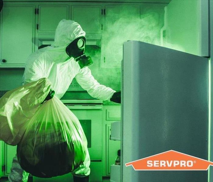 Man in a bio hazard suit cleaning contaminated refrigerator